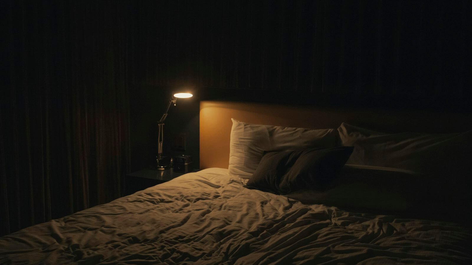 Dark bedroom at night with a bedside lamp switched on